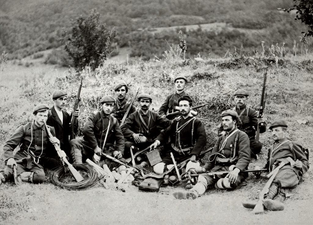 Treća veleška četa – tehničko odeljenje. Četu je predvodio vojvoda Nikola Dečev (sredina, tamna uniforma; 1880.-1903.), anarhista poreklom iz Bugarske (Stara Zagora) koji je bio deo struje koja je i formalno učestvovala u makedonskoj revolucionarnoj organizaciji. Fotografija datira iz 1903 godine, kratko pre nego što su u bitci sa turskom vojskom kod sela Lukovo u blizini Kratova (istočna Makedonija) većina njih poginuli, uključujući i Dečeva. Prvi s leva na slici je Julij Cezar Rozental (sekretar čete; poginuo u istoj bitci sa Dečevom), anarhista i poet poljsko-ruskog porekla. Njegov otac, August Rozental, je bio revolucionar koji je kao organizator jednog ustanka u Ukrajini bio osuđen na smrt, da bi zatim presuda bila zamenjena progonstvom u Sibir. Posle 25 godina sa porodicom uspeva iz Sibira pobeći u Bugarsku gde kao lekar radi po raznim mestima. Obojica su iznimno zaslužni za širenje slobodarskih ideja na ovim prostorima. To naravno nije prošlo neprimećeno od strane vlasti, pa je August Rozental 1889. proteran iz Bugarske u Vranje, gde je i umro.